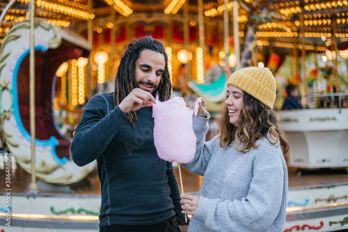 Young couple eating cotton candy at a Christmas fair