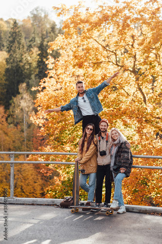 Four joyful friends one of them showing he is flying having a good time spending their holidays together in auturm park in daytime. photo