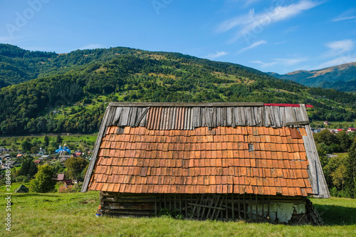 Shepherd's hut with a metal tiled roof on the background of a mountain village.  Kvasy, Zakarpattia region, Ukraine. photo