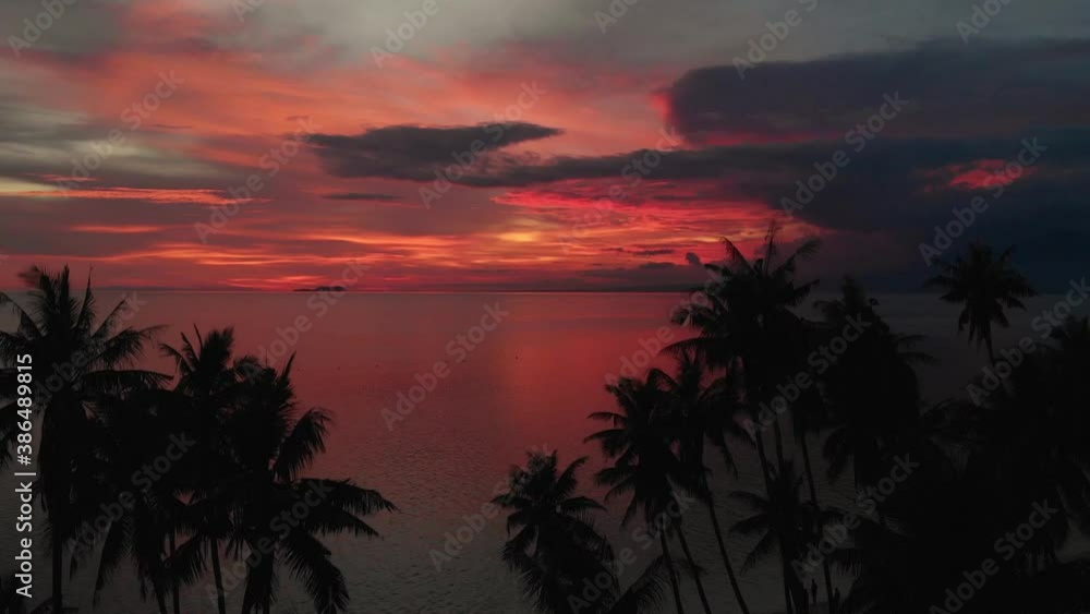 Flying above the ocean at beautiful summer sunset. Palm trees in the background, shot from a drone Flying above the ocean at beautiful summer sunset. Palm trees in the background, shot from a drone