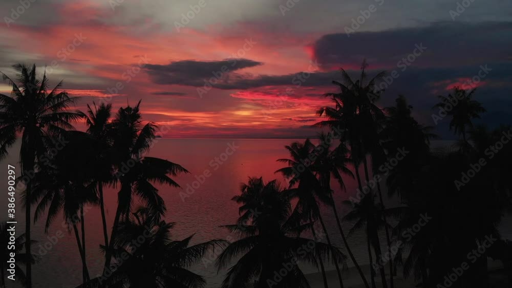 Flying above the ocean at beautiful summer sunset. Palm trees in the background, shot from a drone Flying above the ocean at beautiful summer sunset. Palm trees in the background, shot from a drone