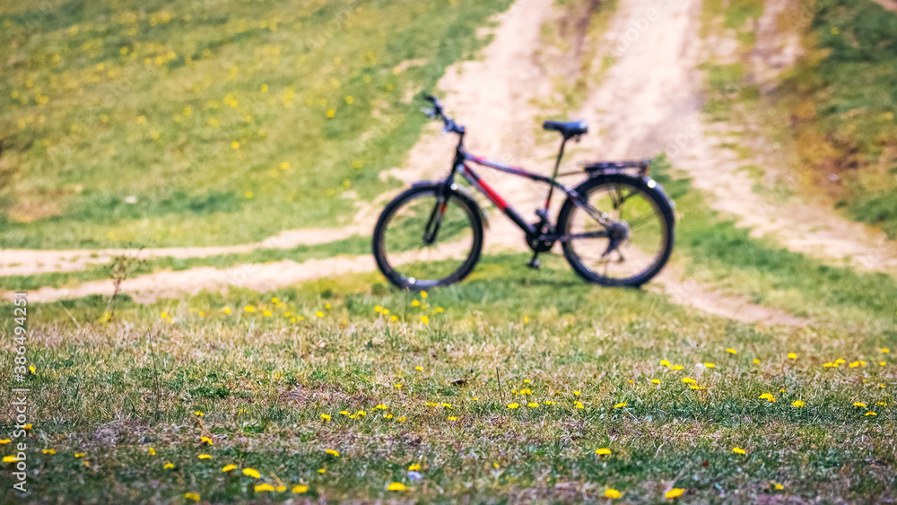 Bicycle in a field among the grass and flowers near a dirt road