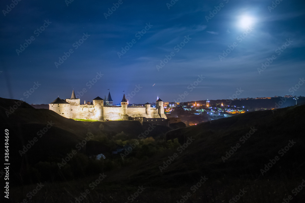 Panoramic  night view of ancient fortress castle in Kamianets-Podilskyi, Khmelnytskyi Region, Ukraine. Old ?astle photo on a postcard or cover. Long exposive