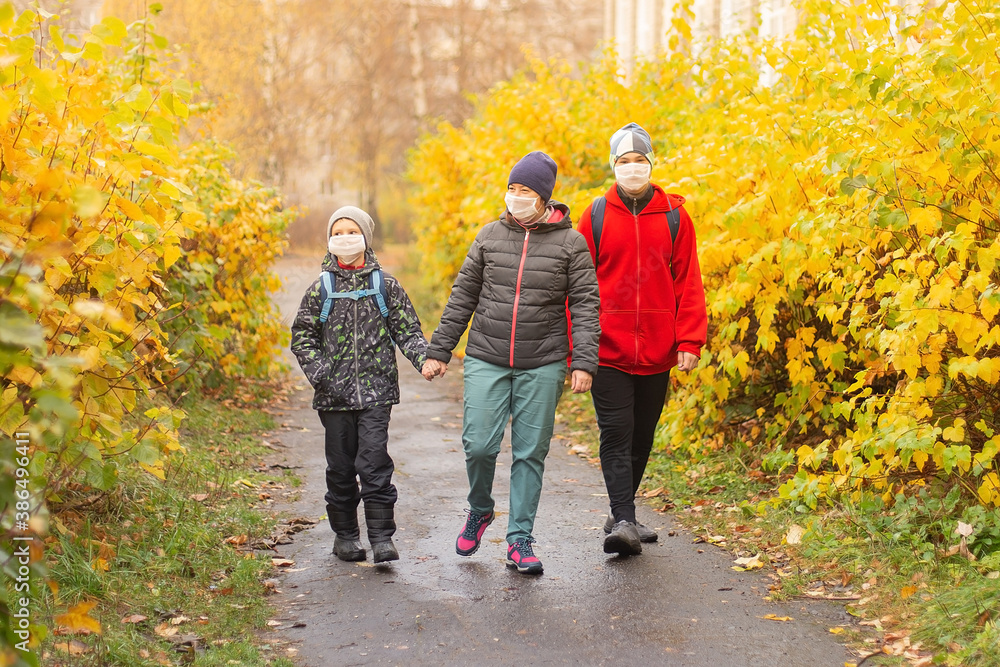Obraz premium mom with two sons in the street wearing protective masks, walking
