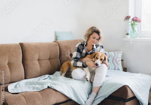 a kind domestic dog lies on the lap of its owner who is sitting at home on the couch