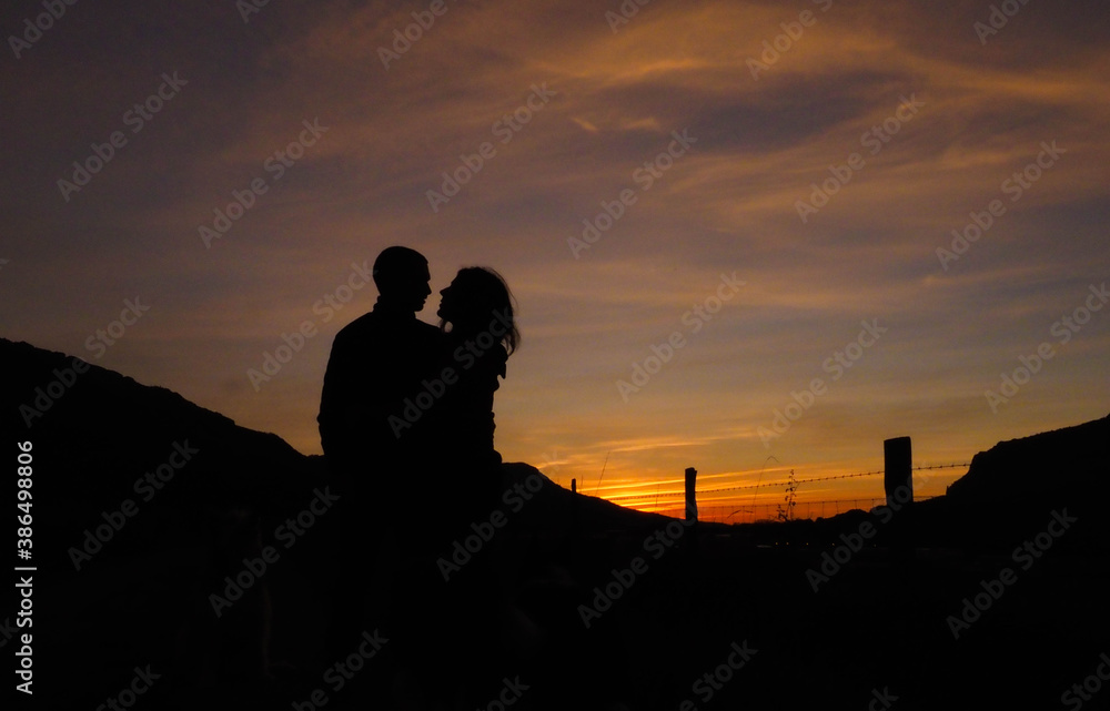 silhouette of a couple with sunsets behind