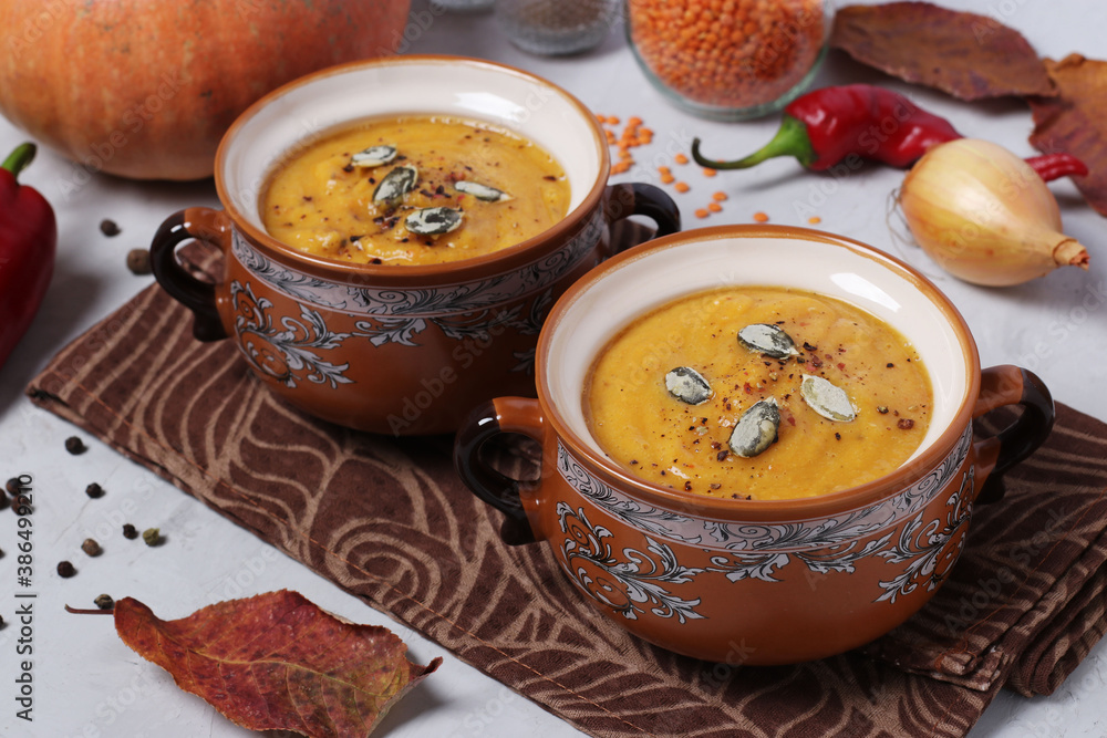 Vegetarian autumn pumpkin soup puree with red lentils in two bowls on gray background. Horizontal format. Closeup Vegetarian autumn pumpkin soup puree with red lentils in two bowls on gray background. Horizontal format. Closeup