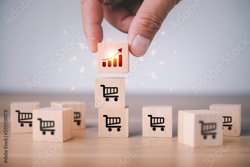 Foto Male hand putting cube with icon growing graph and shopping cart symbol