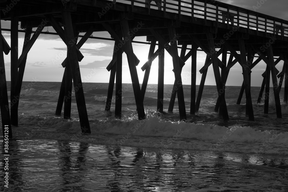 Ocean waves under the fishing pier in black and white