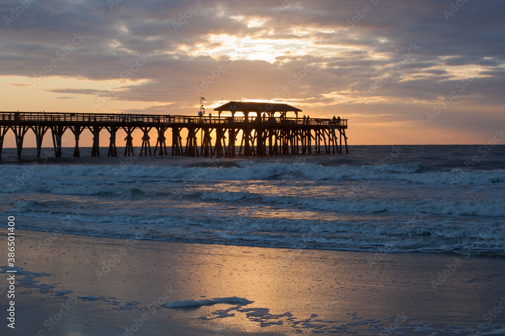 Sunrise with a fishing pier at the ocean