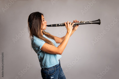 Wall Mural woman playing clarinet on a gray background