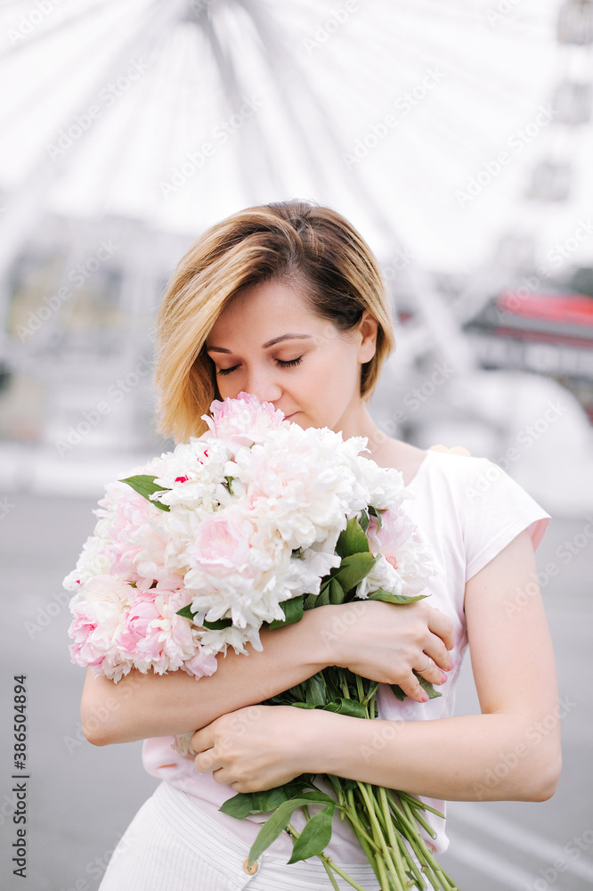 Happy girl with a bouquet of peonies walking through a deserted city in the early morning Happy girl with a bouquet of peonies walking through a deserted city in the early morning
