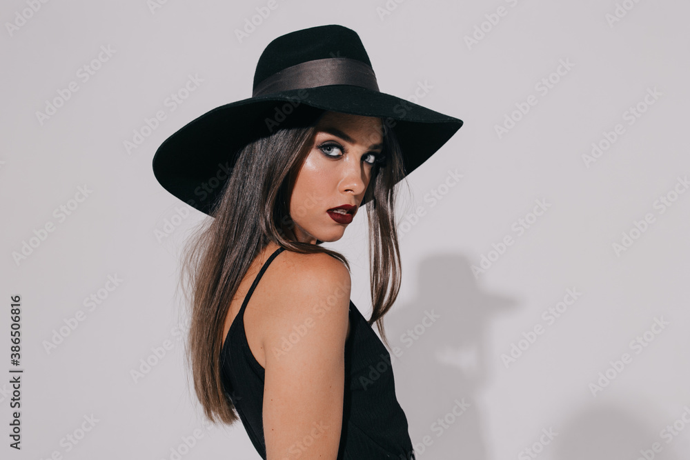 Attractive beautiful elegant woman with evening make up wearing hat looking at camera over isolated background Attractive beautiful elegant woman with evening make up wearing hat looking at camera over isolated background