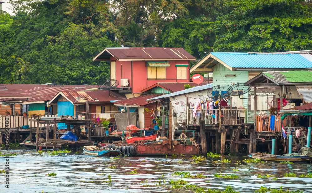 Stilt Houses at a Klong in Bangkok, Thailand. Chao Phraya Riverbank with Lush Vegetation.