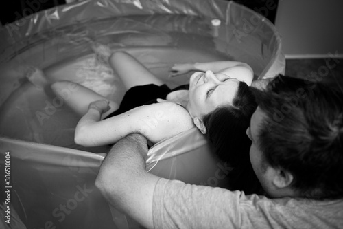 Woman in Labor in Birthing Pool Being Comforted by Husband During at Home Birth photo