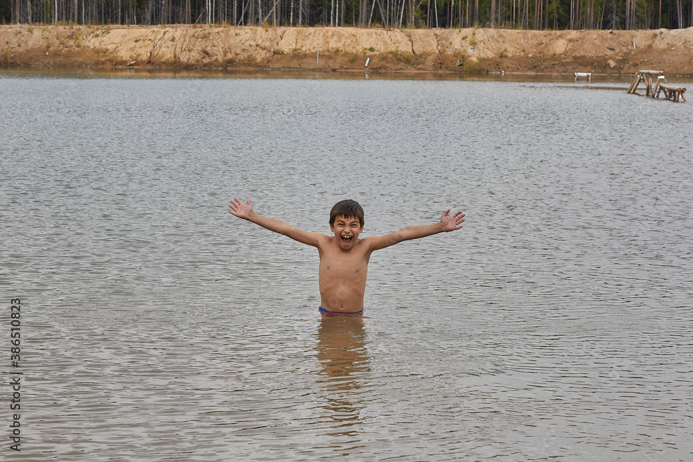 Fototapeta premium boy waist deep in the water of the lake, outdoors in the woods