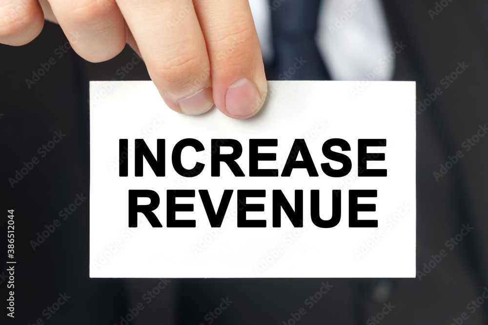 Businessman shows a card with the text INCREASE REVENUE Businessman shows a card with the text INCREASE REVENUE