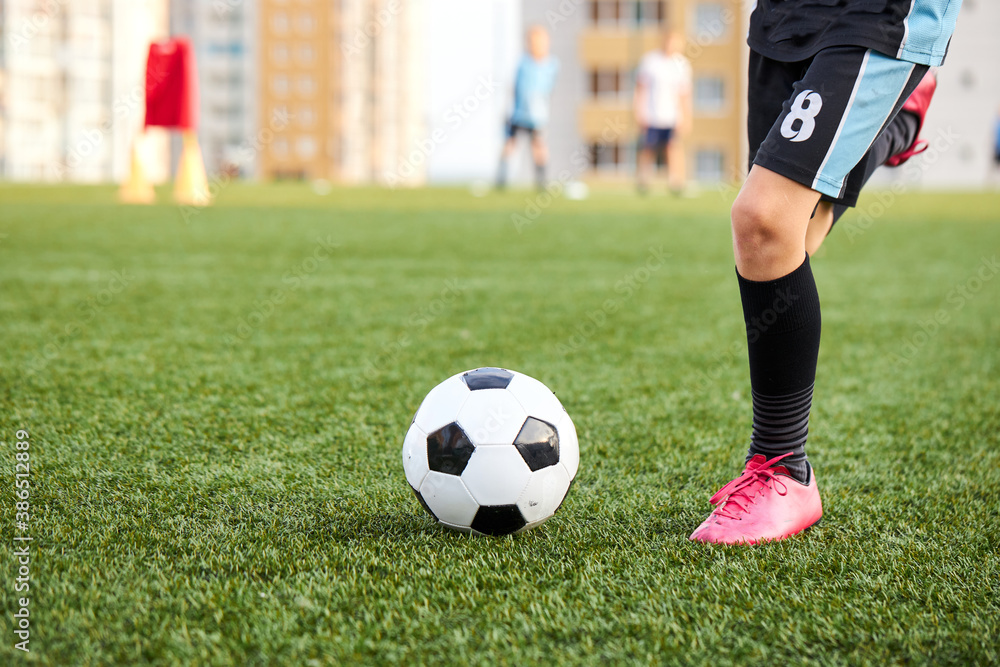 kid boy kicking soccer ball on sports field, cropped child boy in uniform and sneakers play football in stadium kid boy kicking soccer ball on sports field, cropped child boy in uniform and sneakers play football in stadium