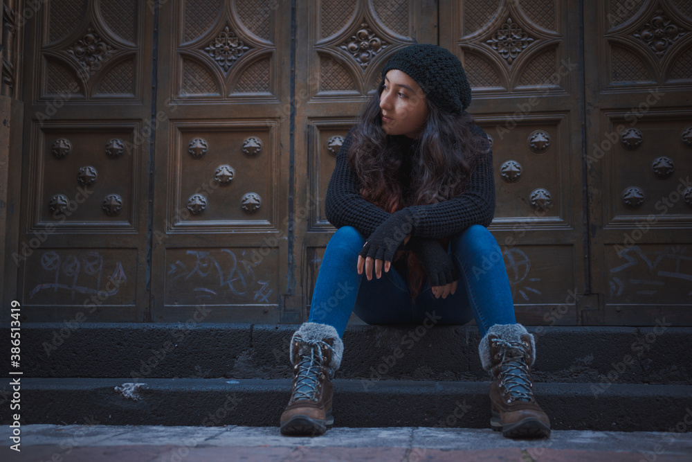 Adolescente sentada en las calles de la Ciudad de México en una tarde de otoño, niña bonita posando sentada con ropa de abrigo
