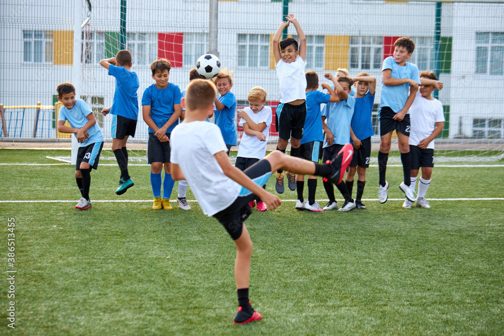 sportive child boy in uniform kicking ball, they have penalty in this round. kids play football, competition in stadium, in field