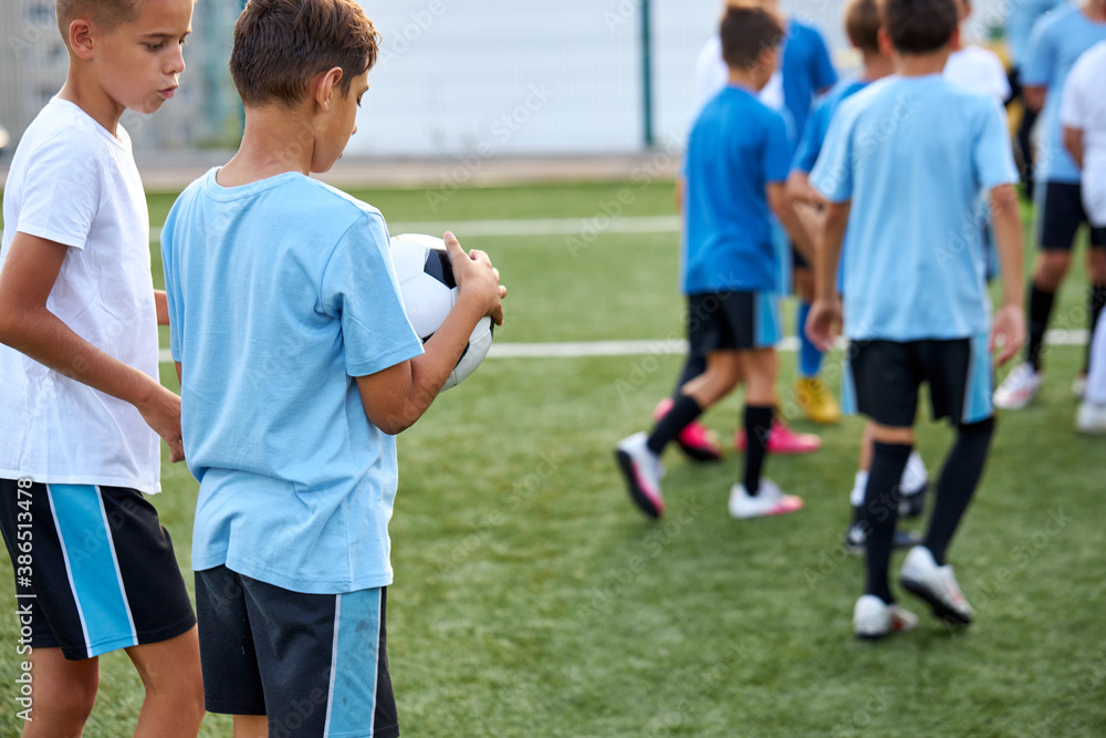 Fototapeta premium young caucasian players on soccer training. kids practicing european football on the grass field in stadium. children lead healthy lifestyle