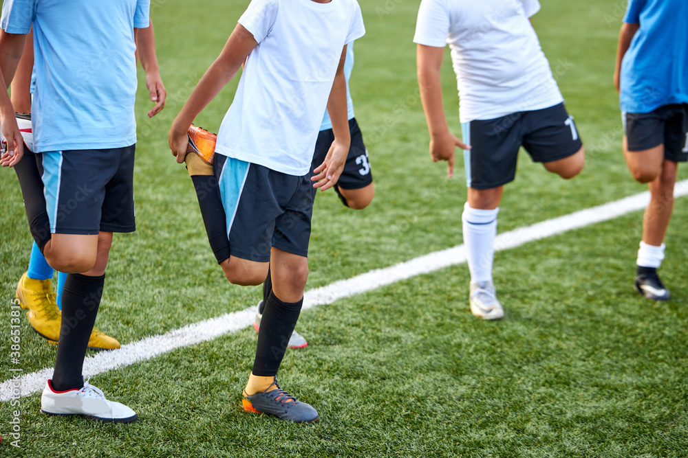 group of caucasian kid boys stretching legs before football game in stadium, they are in special sportive uniform, engaged in sport and healthy lifestyle from childhood group of caucasian kid boys stretching legs before football game in stadium, they are in special sportive uniform, engaged in sport and healthy lifestyle from childhood
