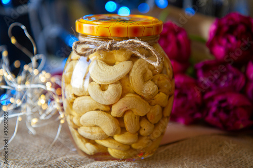 Glass jar with honey and nuts on the background of Christmas. Cashews in honey. Christmas decoration. The concept of healthy eating and healthy foods