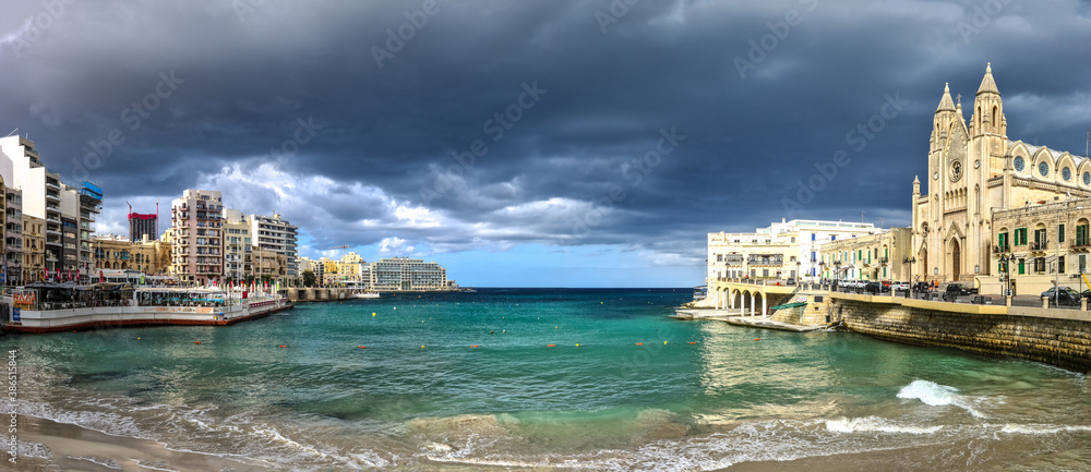 Dark clouds over Balluta Bay in Malta. On the sides of the bay is the Neptunes Waterpolo club and on the other is the parish church of our lady of mount carmel.