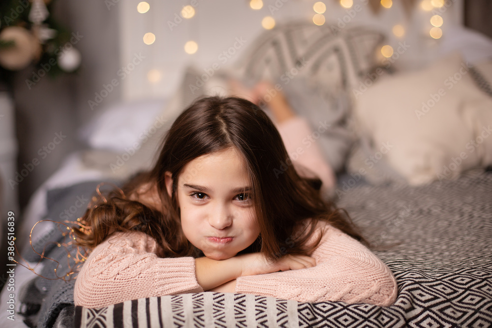 Beautiful little dark-haired girl in the studio with New Year's decor and confetti. The child is having fun and playing. Portrait of a child. Puffed out her cheeks Beautiful little dark-haired girl in the studio with New Year's decor and confetti. The child is having fun and playing. Portrait of a child. Puffed out her cheeks