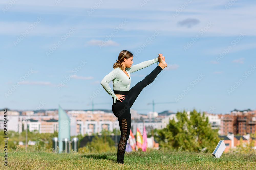 Young sport woman stretching to practice yoga in garden with landscape background Young sport woman stretching to practice yoga in garden with landscape background