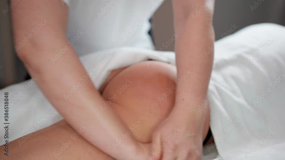 A woman massage therapist makes a powerful anti-cellulite massage of the buttocks to a female client in a cosmetic clinic. Skin care concept. Healthcare and medicine A woman massage therapist makes a powerful anti-cellulite massage of the buttocks to a female client in a cosmetic clinic. Skin care concept. Healthcare and medicine