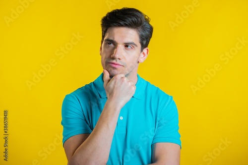 Foto Thinking man looking up and around on yellow background