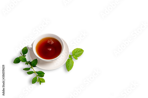 A Cup of black tea on a saucer with mint leaves on a white isolated background. Space for copying.