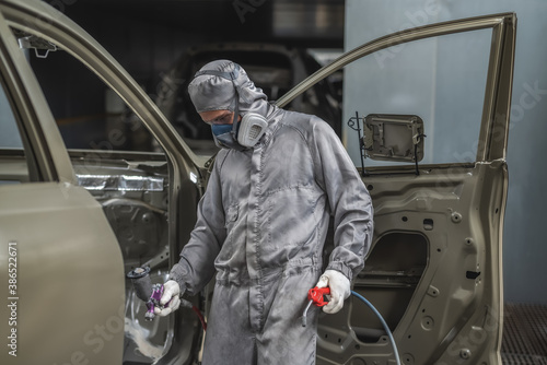 An employee of the paint shop prepares the car body for painting © vadimalekcandr