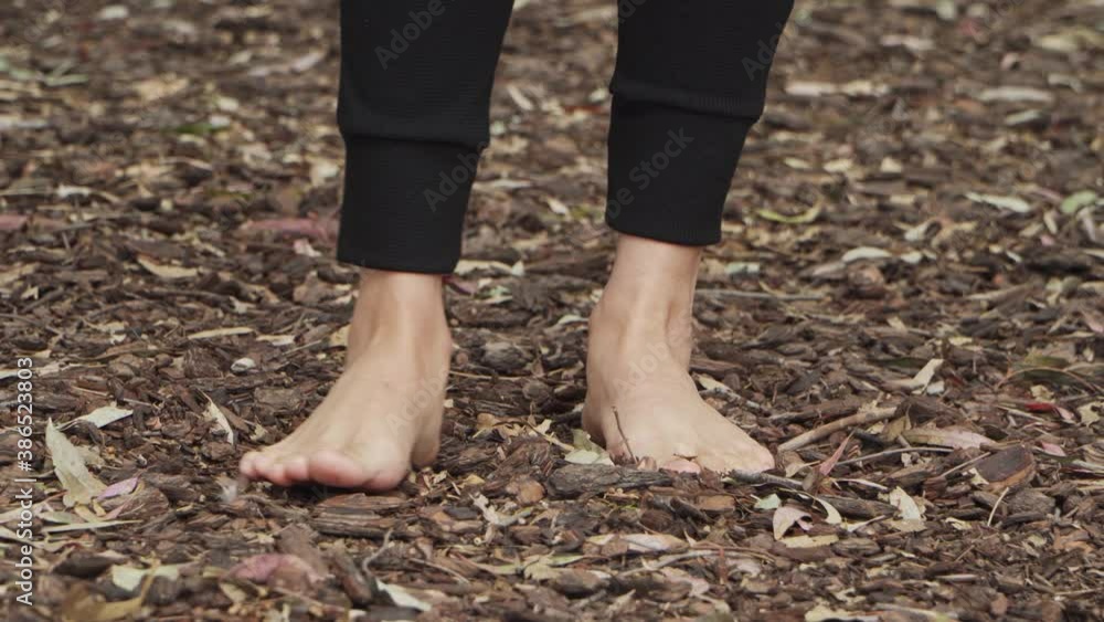 A woman standing barefoot on tree bark floor at the forest and feeling the texture with her toes A woman standing barefoot on tree bark floor at the forest and feeling the texture with her toes