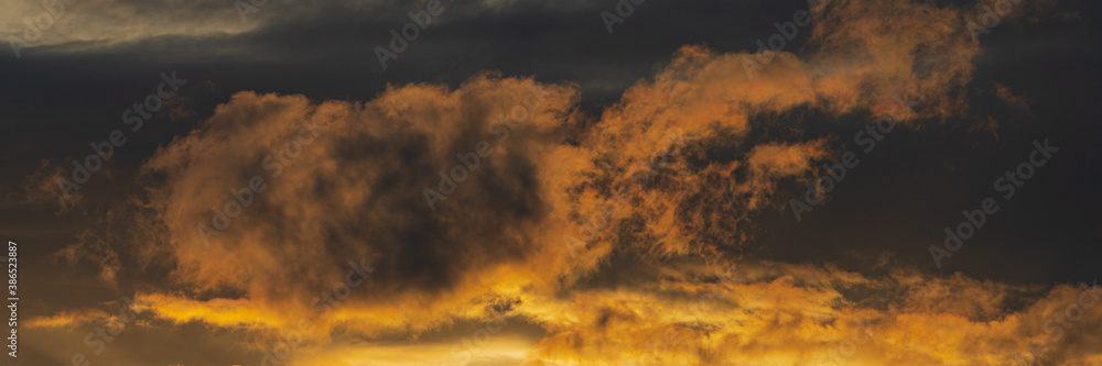 Panoramic view of dramatic clouds illuminated rising of sun in sky to change weather. Soft focus, motion blur sky majestic meteorology cloudscape.