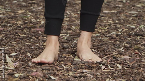 A woman standing barefoot on tree bark floor at the forest and feeling the texture with her toes