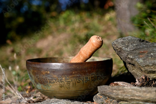 Tibetan singing bowl on a stone. Translation of mantras. transform your impure body, speech and mind