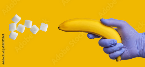 A banana in a hand in a blue medical glove shoots out sugar