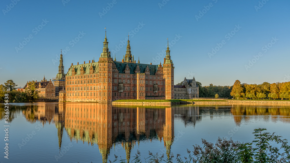 The Royal Frederiksborg Castle in a mirror-gloss reflection at surise