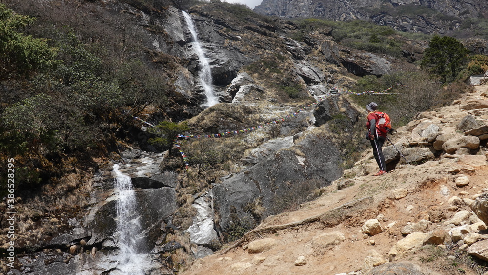 Hiker and the waterfall in mountains in Nepal.
