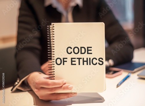 Business woman holding a notebook with the text Code of Ethics