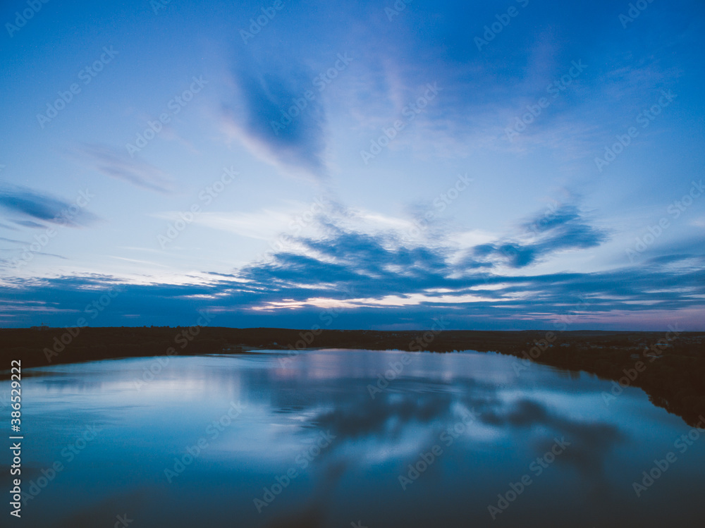 Fototapeta premium Sunset over a river with forest on a horizon. Almost dusk.