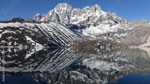 Landscape with snow covered Himalayan mountains that are reflected in a lake in Nepal.