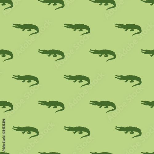Animal seamless pattern and textile design. Vector illustration with green crocodile silhouette on light green background. Good for t-shirt design, fabric print, greeting card, wrapping, wallpapers.
