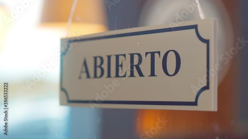 Close up of human turning abierto cerrado sign hanging on glass door of cafe photo