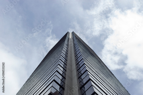 Low angle view of a modern skyscraper corner with blue cloudy sky at background