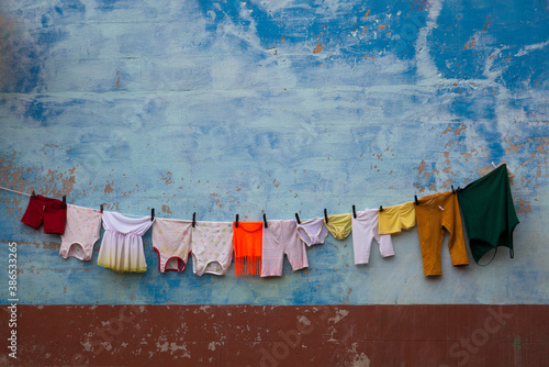 Photography Colorful laundry hangs against a blue, textured wall in Trinidad, Cuba