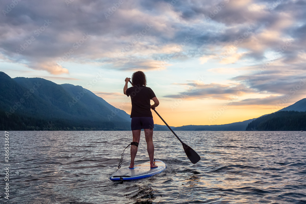 Woman Paddleboarding on Scenic Lake at Sunset in Canadian Nature. Taken in Golden Ears Provincial Park, British Colmbia, Canada.
