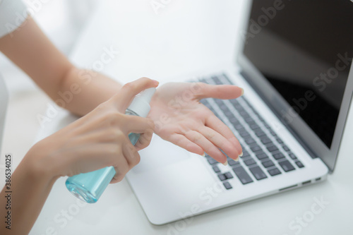 Hand of woman work from home with alcohol gel or sanitizer for cleaning hand and protect coronavirus or covid-19, new normal, quarantine and social distancing, businesswoman using laptop computer.